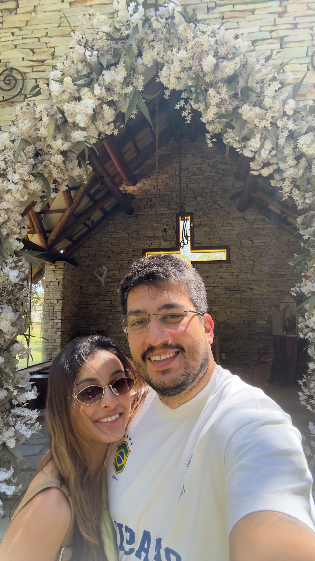 Gabriella e João em uma capela decorada com flores brancas